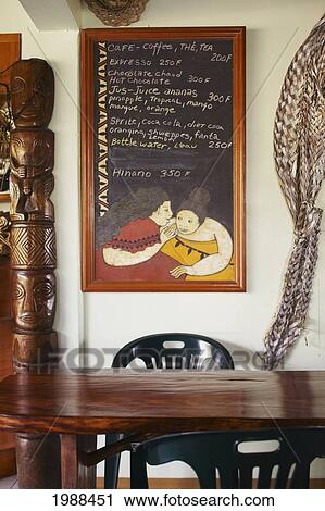 Stock Image - French Polynesia, Tahiti, Huahine, Inside A Coffeeshop, Decorative Wooden Table, Chalkboard Menu On Wall. Fotosearch