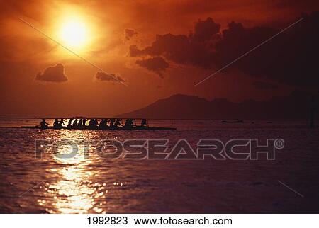 Stock Image - French Polynesia, Tahiti, Moorea, Bora Bora, Outrigger Canoeing At Sunset, Orange Sky.. Fotosearch
