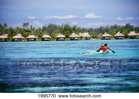 Stock Image - French Polynesia, Tahiti, Moorea, Local People In Canoe Paddling Toward Shore With Bungalows. Fotosearch