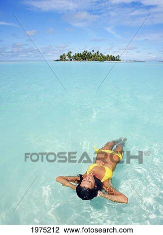 Stock Image - French Polynesia, Tahiti, Moorea, Woman Floating In Water.. Fotosearch