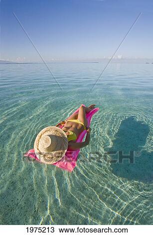 Stock Image - French Polynesia, Tahiti, Moorea, Woman Floating In Water.. Fotosearch