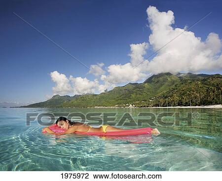 Stock Image - French Polynesia, Tahiti, Moorea, Woman Floating In Water.. Fotosearch