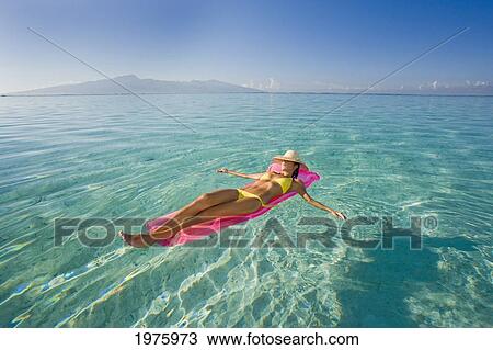 Stock Image - French Polynesia, Tahiti, Moorea, Woman Floating In Water.. Fotosearch