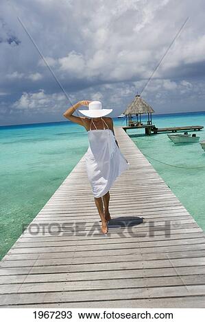 Stock Image - French Polynesia, Tuamotu Islands, Rangiroa Atoll, Woman In White Walking On Ocean Pier.. Fotosearch