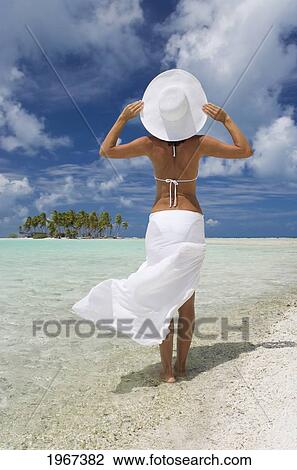 Stock Image - French Polynesia, Tuamotu Islands, Rangiroa Atoll, Woman In White Standing At Ocean's Edge.. Fotosearch