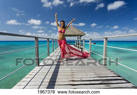 French Polynesia, Tuamotu Islands, Rangiroa Atoll, Woman Walking On Ocean Pier Wearing Pink Pareo. View Large Photo Image Stock Photo - French Polynesia, Tuamotu Islands, Rangiroa Atoll, Woman Walking On Ocean Pier Wearing Pink Pareo.. Fotosearch