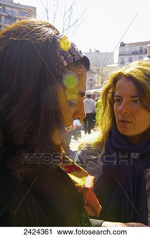 Stock Image - Friends talking with sunlight glowing on their faces; Paris, France. Fotosearch