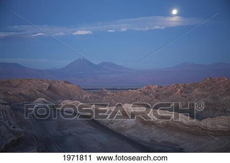 Stock Image - Full Moon Over The Valle De La Luna (Moon Valley) With The Licancabur Volcano In The Background At Dusk, San Pedro De Atacama, Antofagasta Region, Chile. Fotosearch
