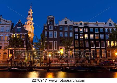 Stock Photo - Gabled houses at dusk with the spire of the Zuiderkerk church behind; Amsterdam, Holland. Fotosearch