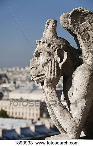 Stock Image - Gargoyle Overlooking Paris With It's Tongue Sticking Out; Paris, France. Fotosearch