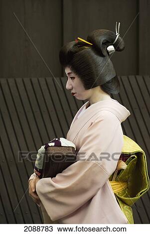 Stock Image - Geisha Walking In A Street; Kyoto, Japan. Fotosearch