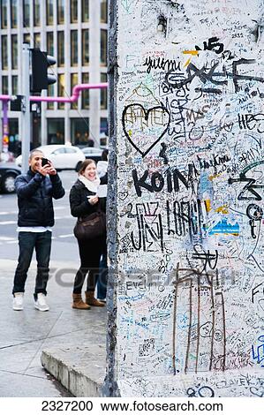 Stock Image - Germany, Berlin, Iron Curtain; Potsdamer Platz, Tourists watching pieces of original Berlin Wall. Fotosearch