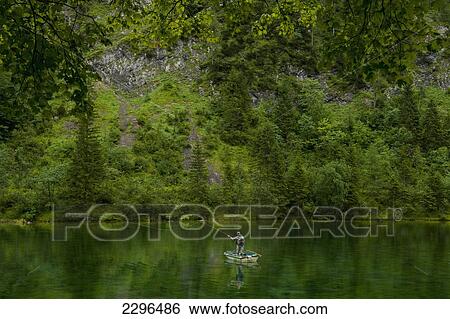 Stock Photograph - Germany, Man fly fishing from small boat in Lake Forggensee near Ruhpolding; Bavaria. Fotosearch