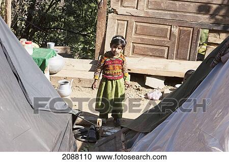 Stock Image - Girl By A Home Destroyed By The 8 October 2005 Earthquake, As Seen From The Chikar To Saran Road, Azad Kashmir, Pakistan. Fotosearch