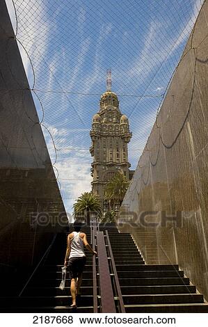 Stock Photo - Girl Coming From The Mausoleum Under General Artigas Statue And Salvo Palace, Historical Building Built In 1922-28, Eclecticism Style, Montevideo, Uruguay, South America. Fotosearch
