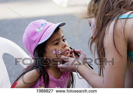 Stock Photo - Girl getting her face painted by a woman, Valparaiso, Chile. Fotosearch