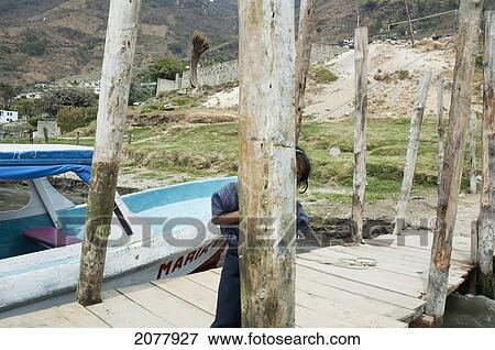 Stock Photo - Girl Hiding On A Dock, Santiago De Atitl. Fotosearch