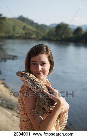 Stock Image - Girl holding a lizard; Thaton, Chiang Rai, Thailand. Fotosearch
