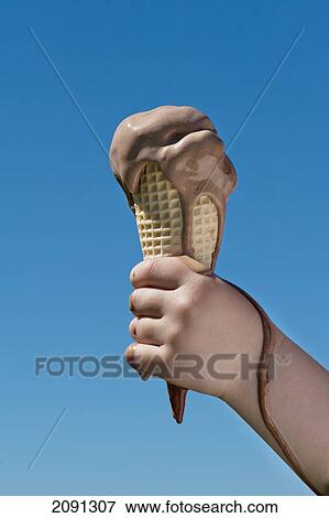 Stock Photo - Girl Holding A Melting Ice Cream Against A Blue Sky, West Sussex, Uk. Fotosearch