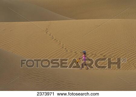 Girl in pink swimsuit with bucket and spade walking across sand dunes at dusk; Dubai, United Arab Emirates View Large Photo Image Stock Image - Girl in pink swimsuit with bucket and spade walking across sand dunes at dusk; Dubai, United Arab Emirates. Fotosearch