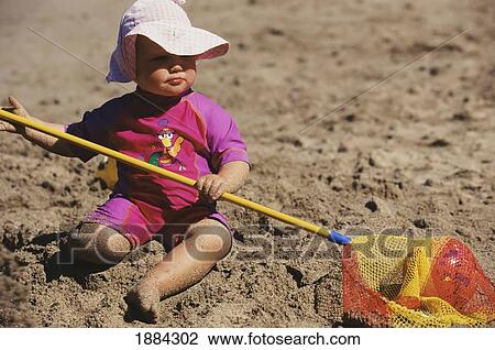 Stock Image - Girl In Wet Suit On The Beach Holding A Net. Fotosearch