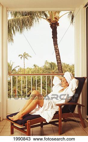 Stock Image - Girl In White Robe Relaxing On Resort Suite Veranda Lounge Chair. Fotosearch