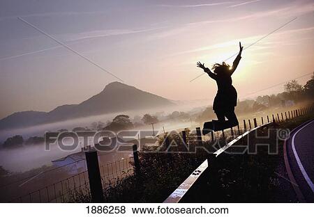 Stock Photo - Girl Jumping On A Country Road At Dawn. Fotosearch