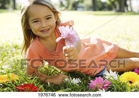 Stock Photograph - Girl Playing With Flowers In Grass. Fotosearch