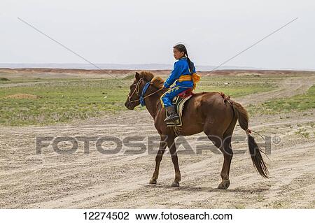 Stock Image - Girl riding a horse at the Naadam Festival in Mandal Ovoo,? mnÃƒÆ’Ã‚Â·govi Province, Mongolia. Fotosearch