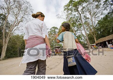 Girl Selling Souvenir To Female Tourist, Rear View, Angkor, Siem Reap, Cambodia View Large Photo Image Stock Photo - Girl Selling Souvenir To Female Tourist, Rear View, Angkor, Siem Reap, Cambodia. Fotosearch