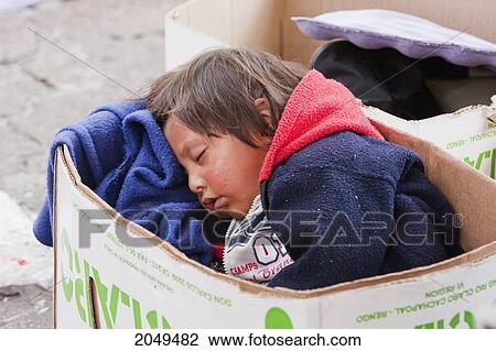 Stock Image - Girl Sleeping In A Cardboard Box, Otavalo, Imbabura, Ecuador. Fotosearch