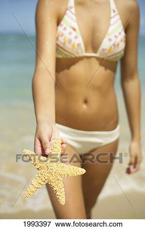 Girl Standing On Tropical Beach Holding Out A Starfish, Legs And Torso View Large Photo Image Stock Photo - Girl Standing On Tropical Beach Holding Out A Starfish, Legs And Torso. Fotosearch