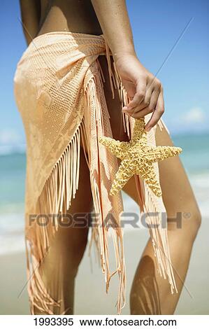 Girl Standing On Tropical Beach Wearing Pareo, Holding A Starfish, Legs And Torso View Large Photo Image Stock Photography - Girl Standing On Tropical Beach Wearing Pareo, Holding A Starfish, Legs And Torso. Fotosearch