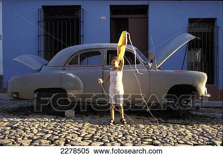 Stock Photography - Girl with kite standing in front of wrecked 50. Fotosearch