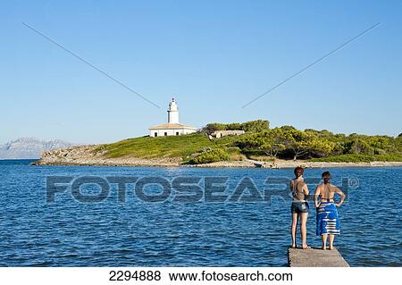 Girls Enjoying The View Of Alcanada Island And Its Lighthouse Near Alcudia, Mallorca, Balearic Islands, Spain View Large Photo Image Stock Photo - Girls Enjoying The View Of Alcanada Island And Its Lighthouse Near Alcudia, Mallorca, Balearic Islands, Spain. Fotosearch