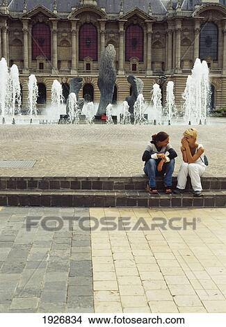 Picture - Girls Sitting In Front Of Fountain. Fotosearch