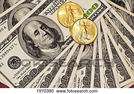 Stock Image - Gold Coins On A Pile Of Hundred Dollar Bills. Fotosearch