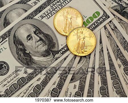 Stock Photo - Gold Coins On A Pile Of Hundred Dollar Bills.. Fotosearch