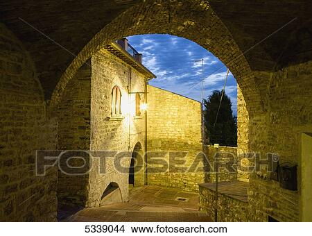 Picture - Golden lights illuminate historic buildings and walkway; Assisi, Umbria, Italy. Fotosearch