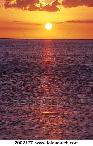 Stock Photo - Golden Sun Ball, Sunset With Orange Sky Over Ocean Purple Surface With Reflections. Fotosearch