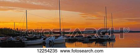 Stock Photography - Golden sunset over a lake with boats; Knowlton, Quebec, Canada. Fotosearch