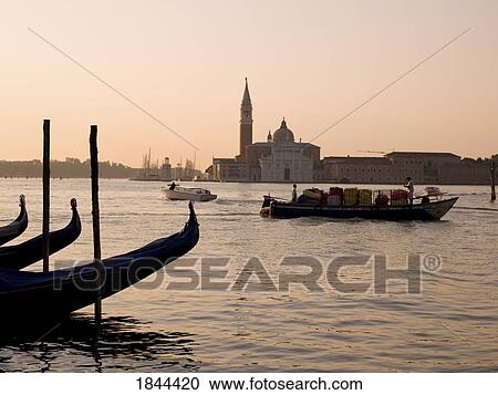 Stock Image - Gondolas And Boats On Canal, Church Of St. Giorgio Maggiore In Background; Grand Canal, Venice, Italy. Fotosearch