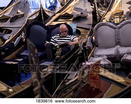 Stock Photograph - Gondolier Reading Magazine; Venice, Italy. Fotosearch
