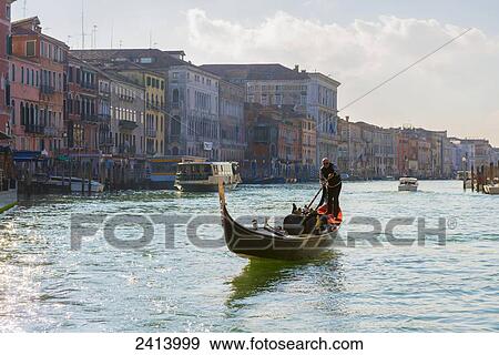 Stock Photo - Gondolier rows in a gondola in the grand canal; Venice, Veneto, Italy. Fotosearch