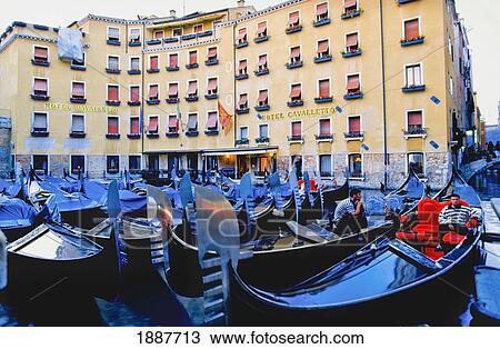 Stock Image - Gondoliers Sitting In Gondolas In Front Of Hotel Cavalletto. Fotosearch