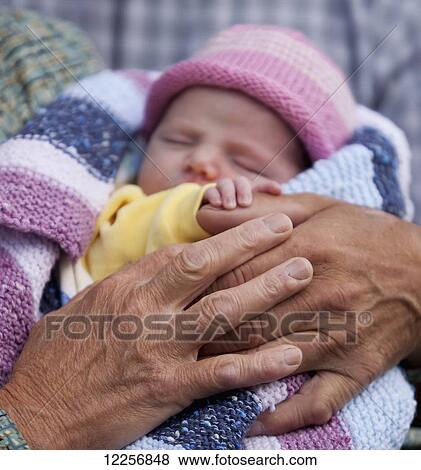 Stock Photo - Grandmother holding her newest one month old grandchild; Surrey, British Columbia, Canada. Fotosearch