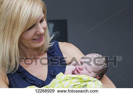 Stock Photo - Grandmother holding newborn granddaughter in birthing room; Edmonton, Alberta, Canada. Fotosearch