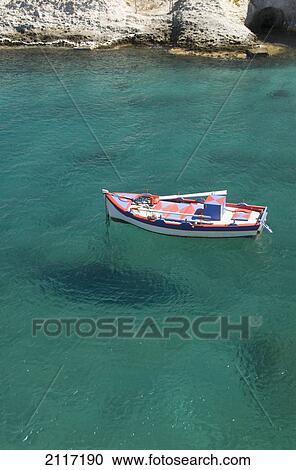 Stock Image - Greece, Cyclades, Island of Milos, Boat off the shore of Mitakes Village.. Fotosearch