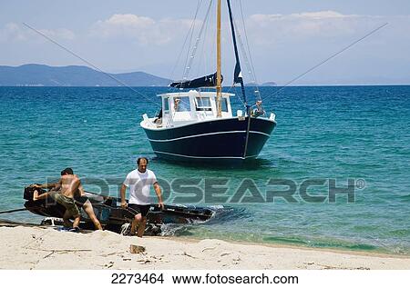 Picture - Greece, Halkidiki, New traditional style wooden pleasure boat being launched into the sea outside some boat building premises; Ierissos. Fotosearch