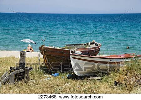 Greece, Halkidiki, Small boats on the beach and sunbathers under a parasol; Ierissos View Large Photo Image Stock Photo - Greece, Halkidiki, Small boats on the beach and sunbathers under a parasol; Ierissos. Fotosearch